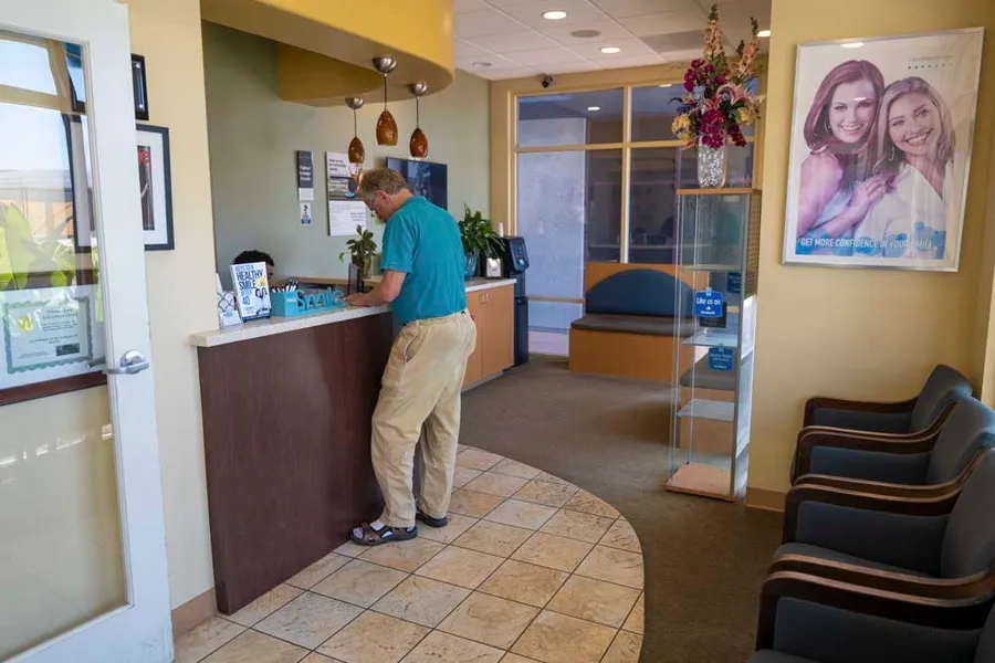 A man is standing at a counter in a dental office.
