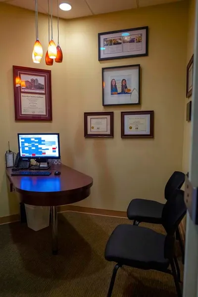 A room with a desk and chairs and a computer on it