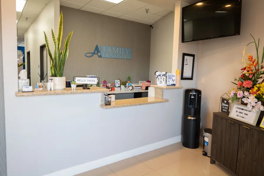 A dental office with a reception desk and a tv on the wall.