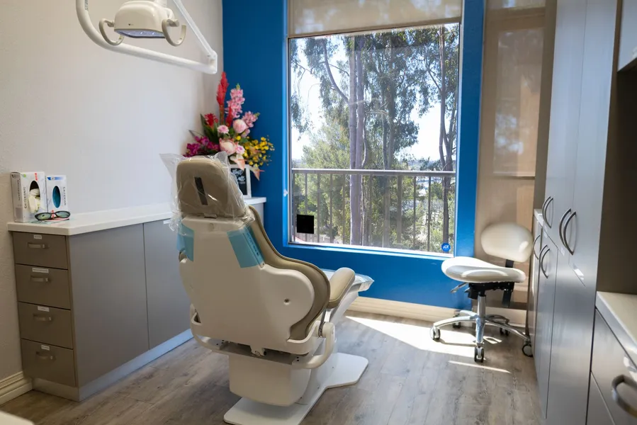 A dental office with a dental chair and a window.