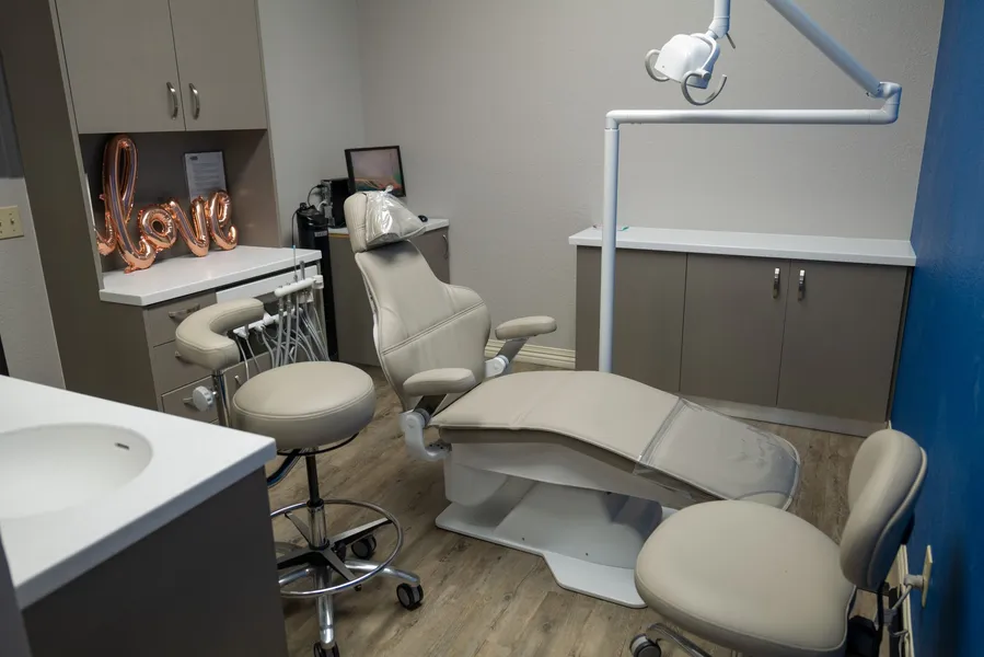 A dental office with a dental chair and a sink.