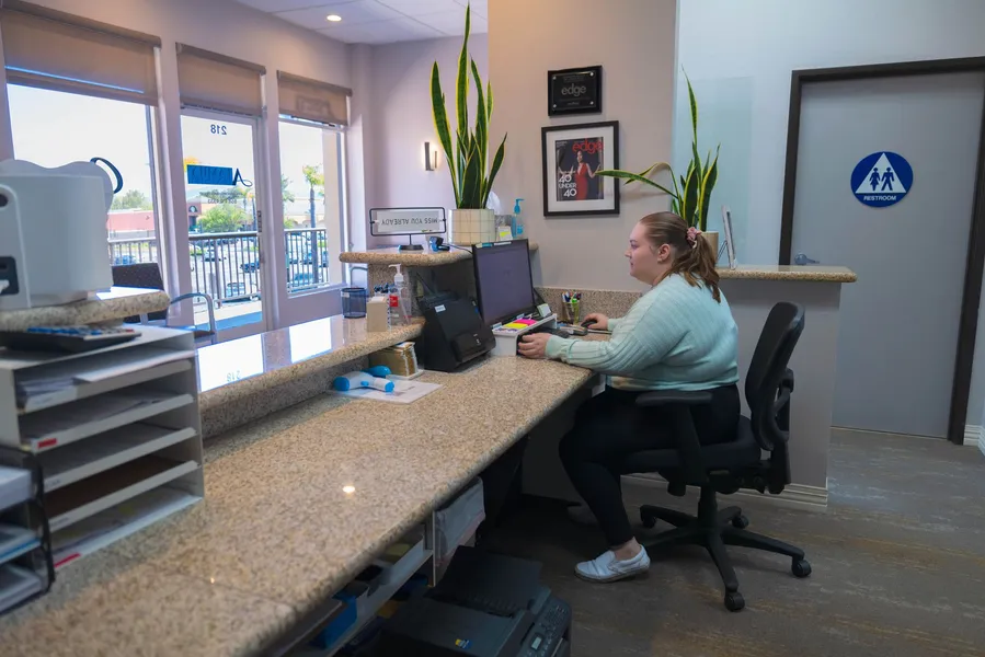 A woman is sitting at a desk in front of a computer.